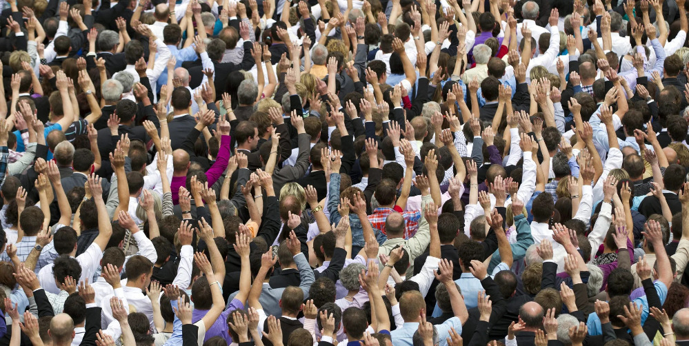 Folla di persone che alzano la mano